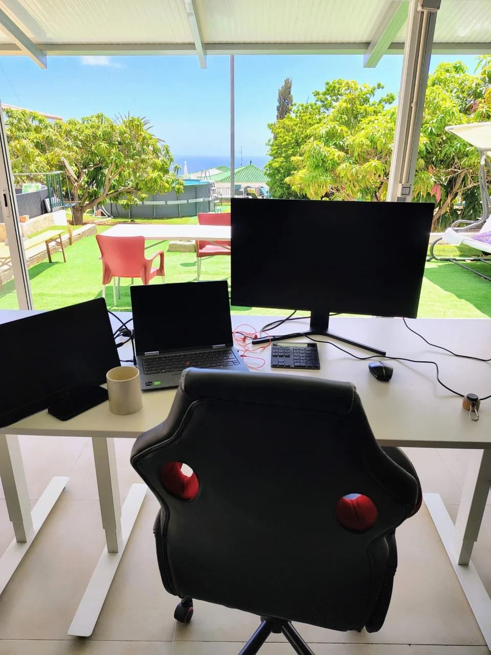 A laptop and monitors on a desk overlooking the garden, pool and Atlantic at Blue Paradise
