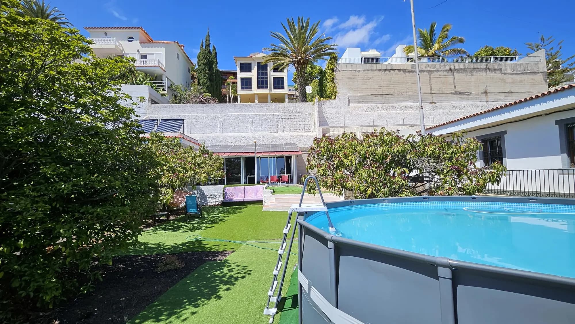 Terrasse piscine de Blue Paradise avec transats et vues sur le jardin.